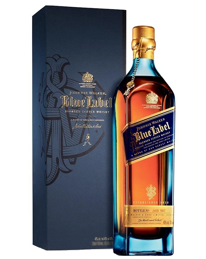 A imagem mostra uma garrafa de whisky Johnnie Walker Blue Label, um Blended Scotch Whisky. A garrafa possui um rótulo azul escuro com detalhes dourados, refletindo a elegância e a exclusividade deste whisky premium. 