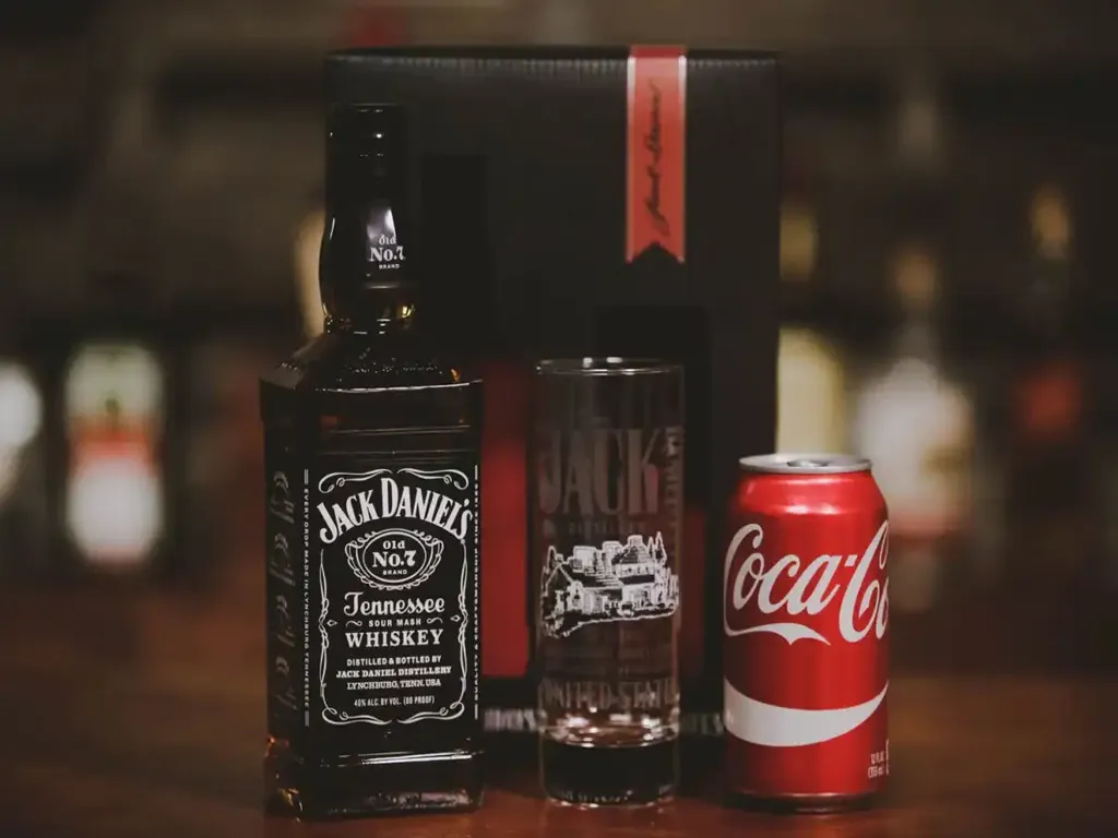 Garrafa de whisky Jack Daniel's com lata de Coca-Cola e copo