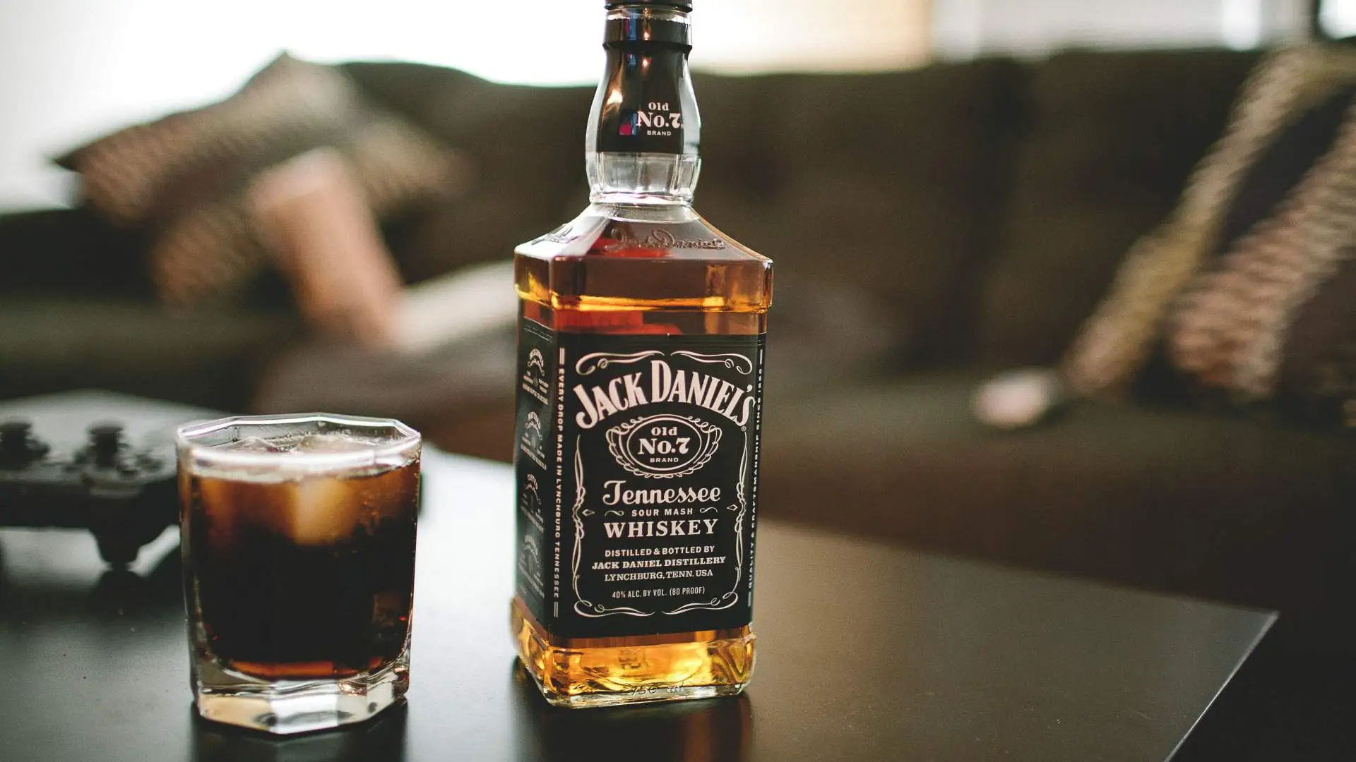 Garrafa de whisky Jack Daniel's Tennessee e copo com whisky e gelo em uma mesa de centro.