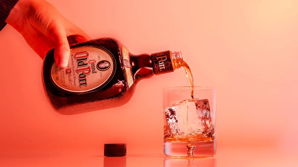 Whisky Old Parr 12 anos sendo servido em um copo com gelo.