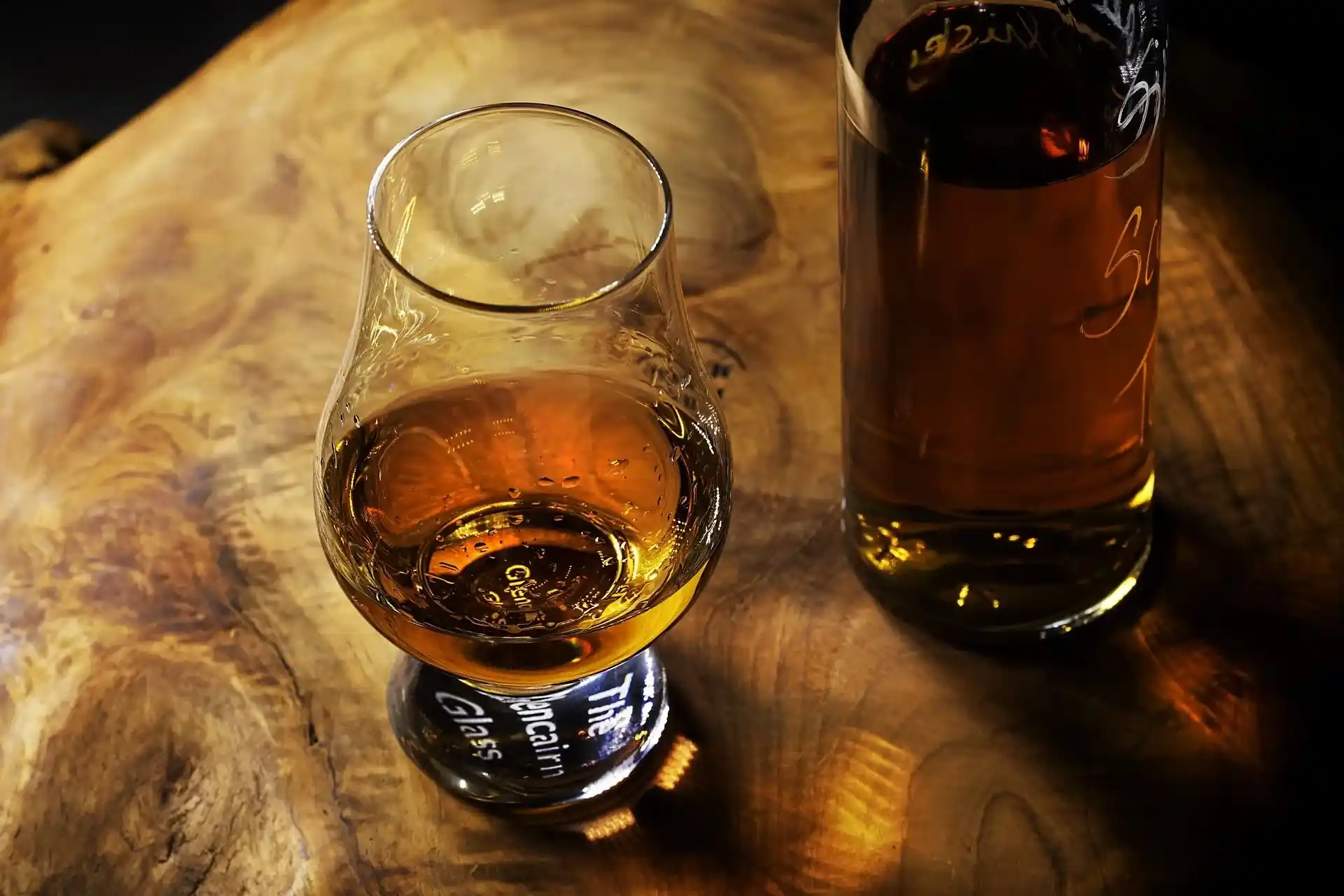 Melhores whiskys para beber puro: 8 seleções atualizadas com copo de whisky em destaque ao lado de uma garrafa.