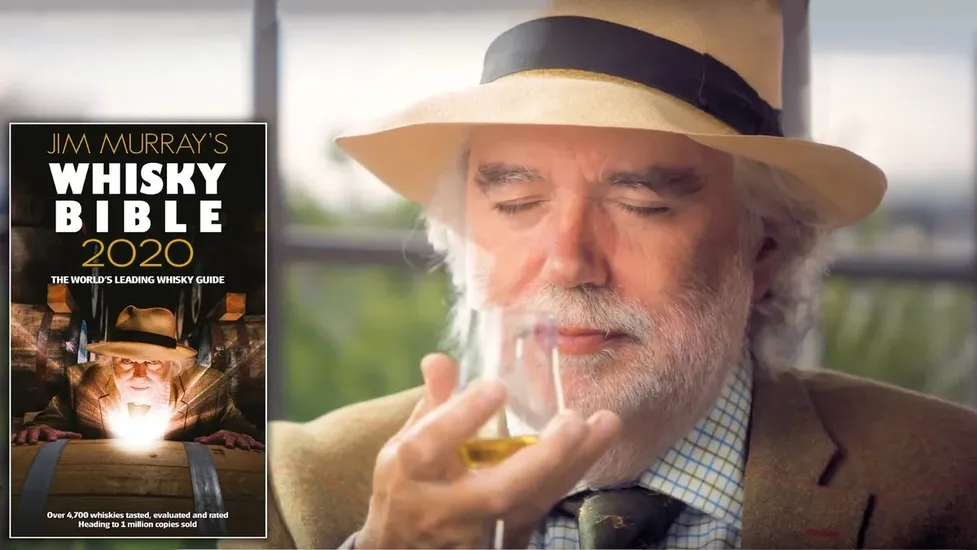 Jim Murray degustando whisky ao lado da capa do livro Whisky Bible 2020.