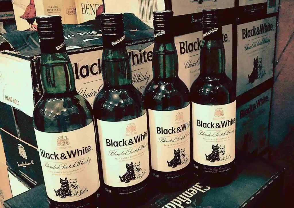 Garrafas de Whisky Black & White em prateleira.