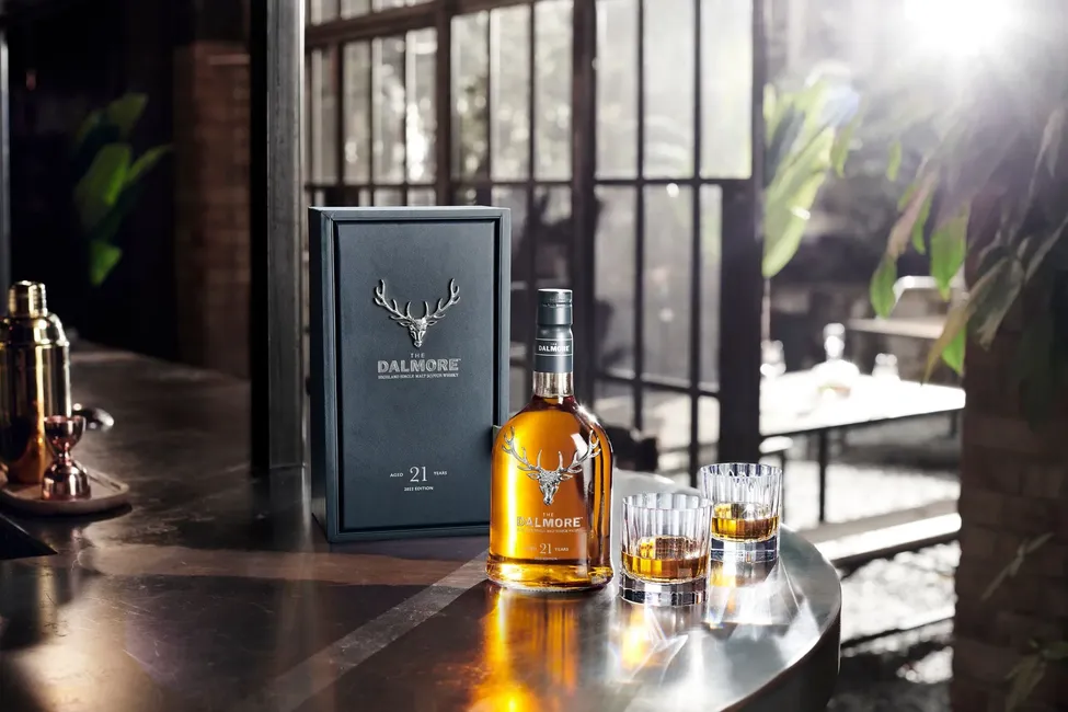 Garrafa de whisky Dalmore 21 anos com dois copos de whisky em um ambiente sofisticado.