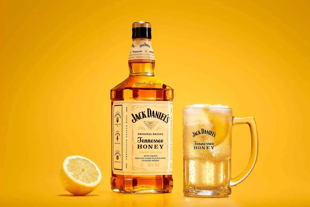 Garrafa de Whisky Jack Daniel's Tennessee Honey com copo de bebida e fatia de limão.