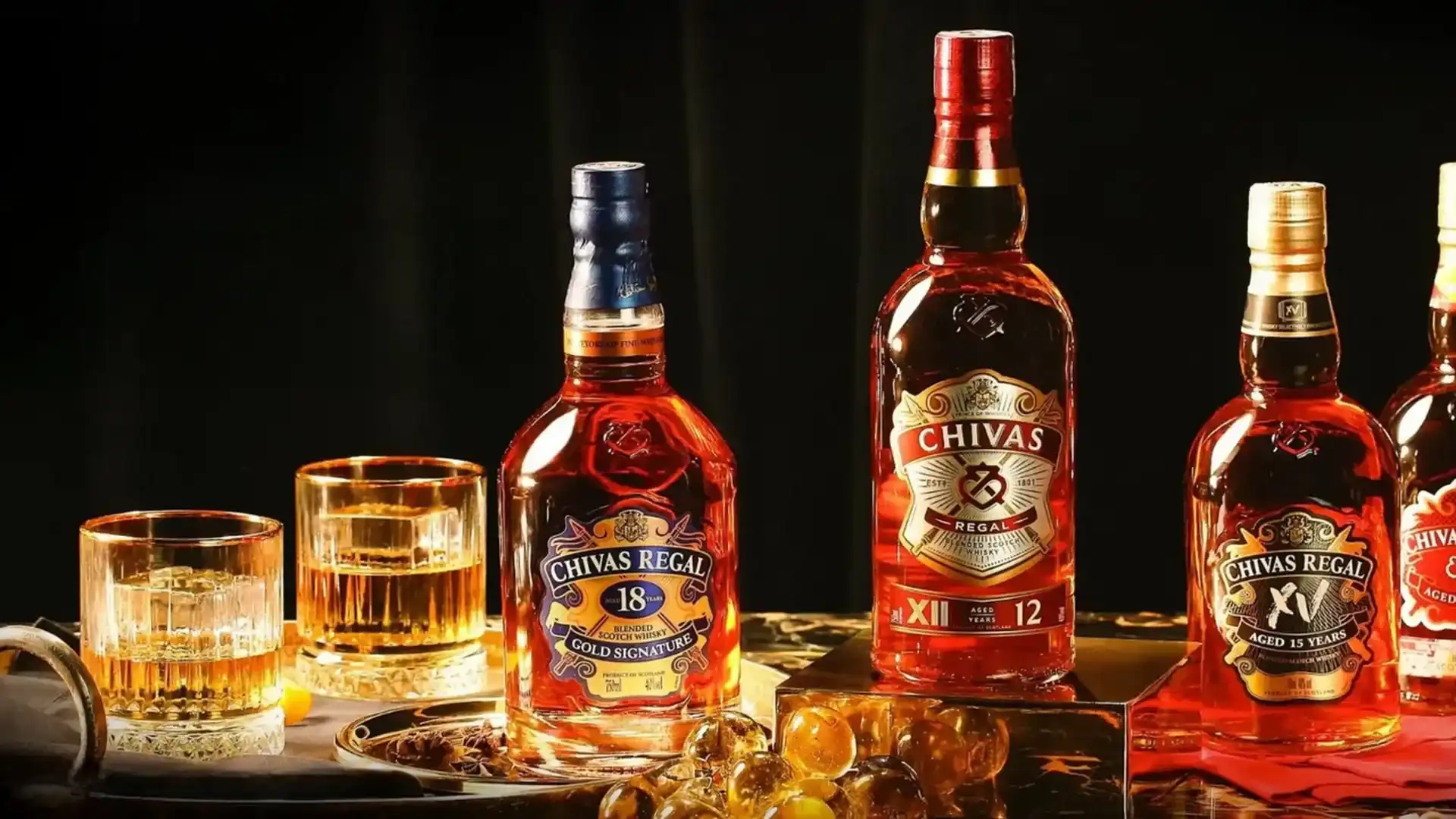 Garrafas dos whiskys Chivas Regal 12, 15 e 18 anos acompanhadas de copos, destacando os melhores whiskys Chivas.