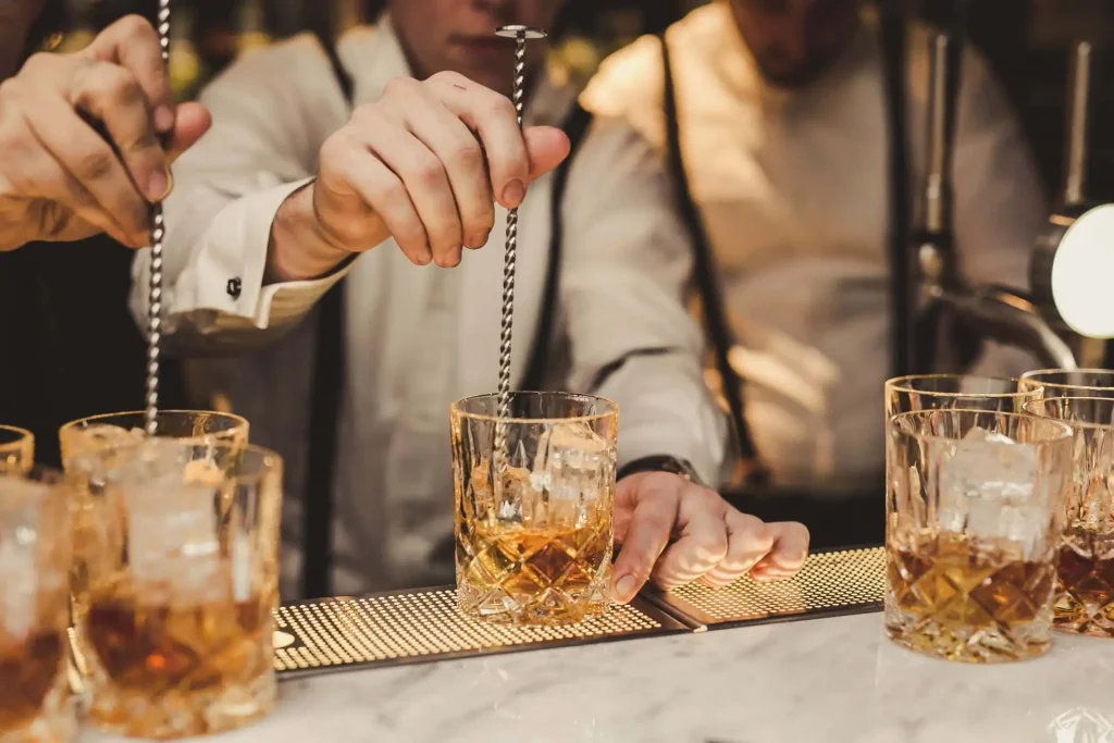 Bartenders preparando coquetéis com whisky, destacando os whiskys mais vendidos no Brasil.