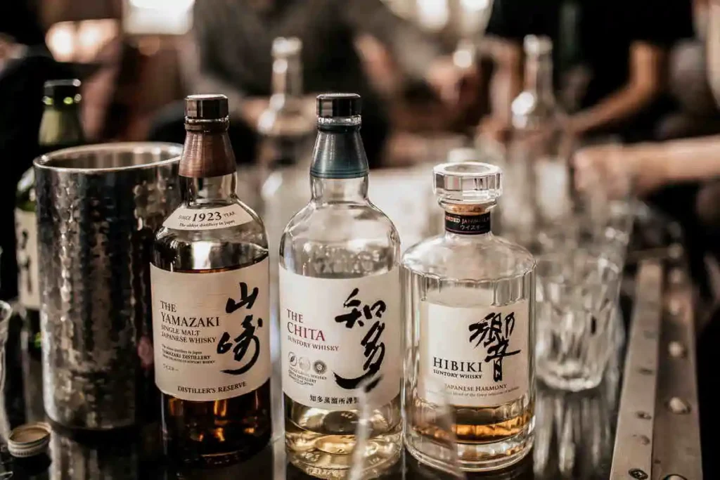 Garrafa de whisky The Chita ao lado de outros rótulos japoneses renomados, destacando sua elegância e suavidade.