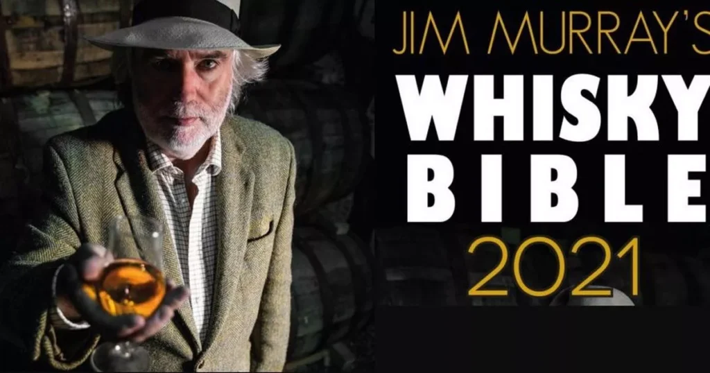 Jim Murray segurando taça de whisky ao lado da capa da Whisky Bible 2021 com destaque ao Talisker 10 Anos.